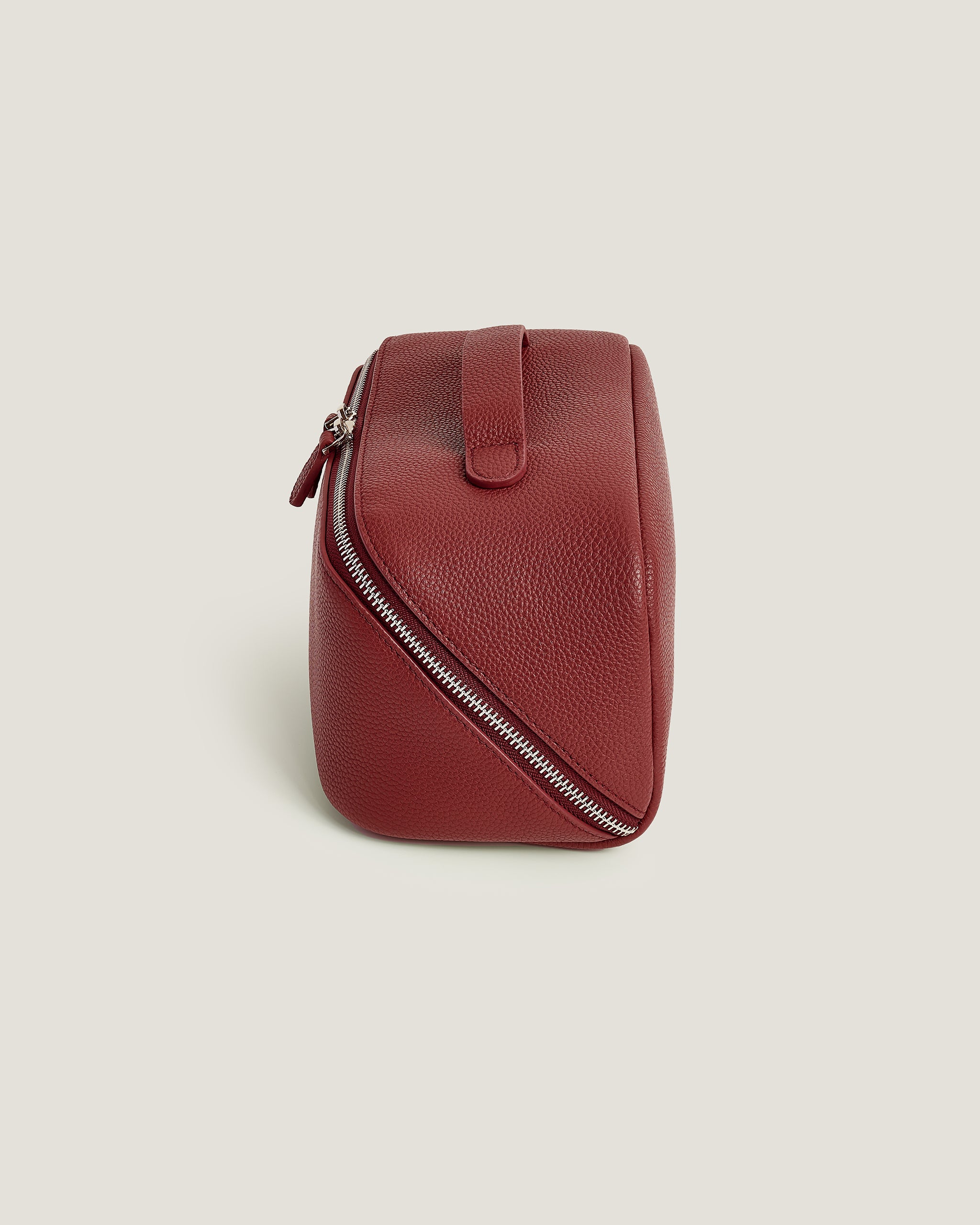 Red leather makeup bag with a zipper on a beige background
