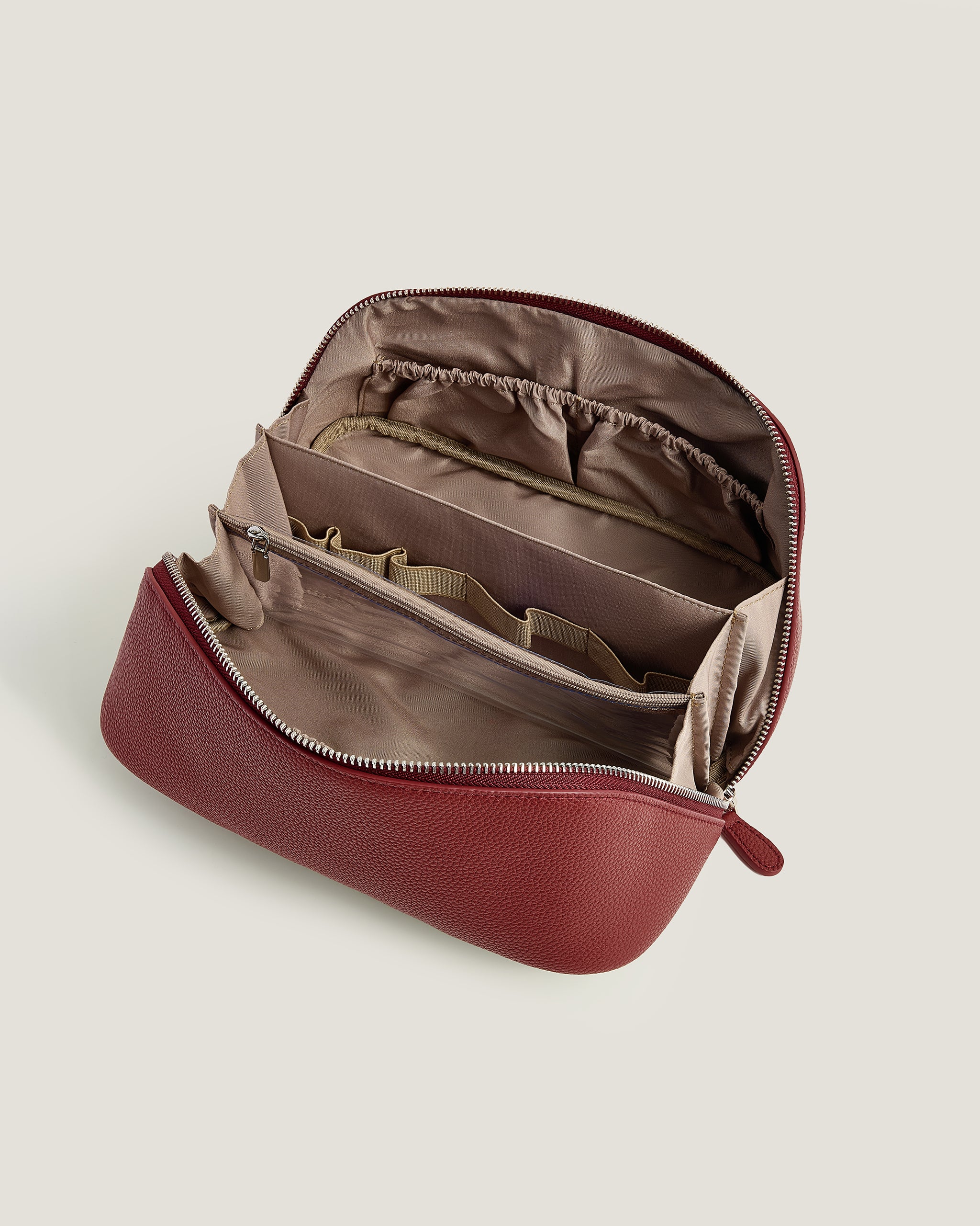 Red makeup bag with interior compartments on a beige background