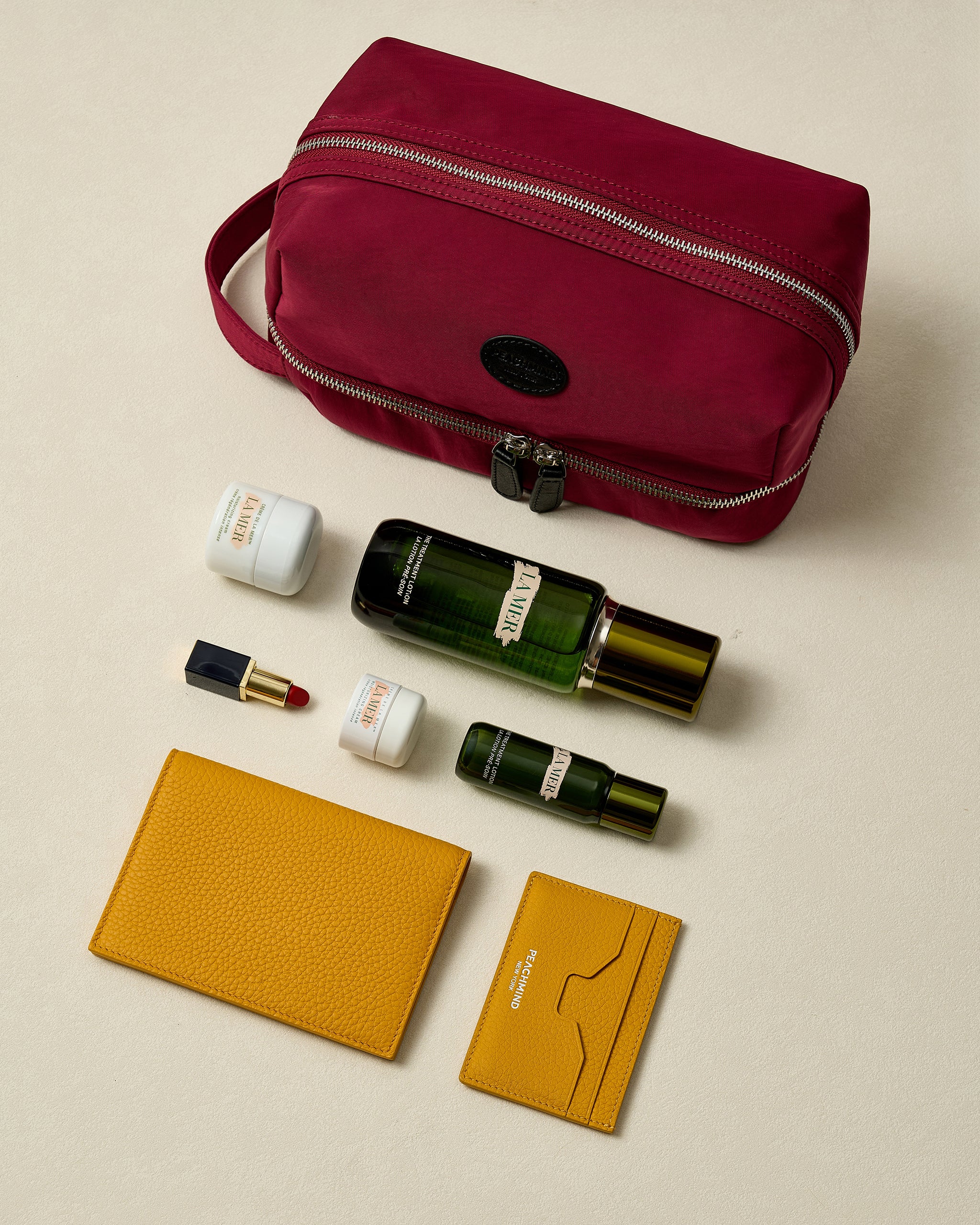Red toiletry bag with cosmetic items on a beige background