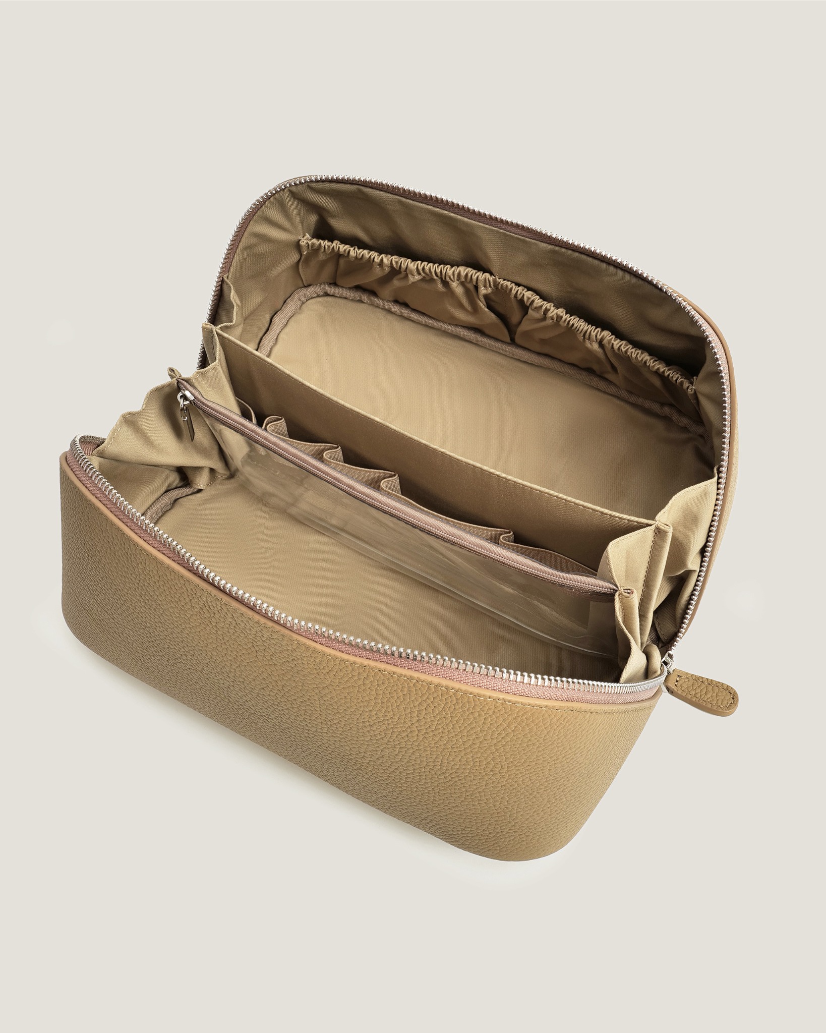 Open beige makeup bag with interior compartments on a light beige background