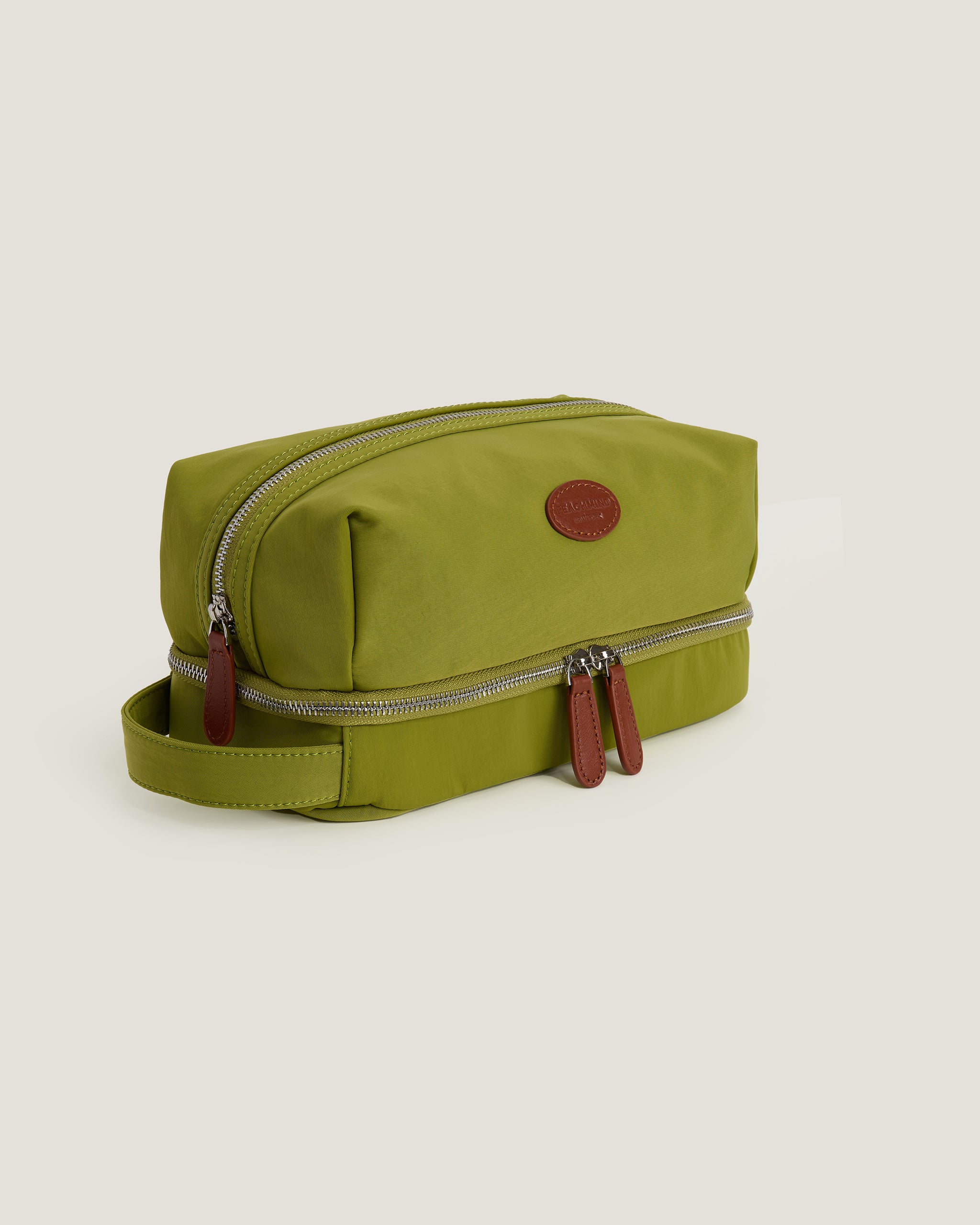 Green toiletry bag with a strap on a beige background