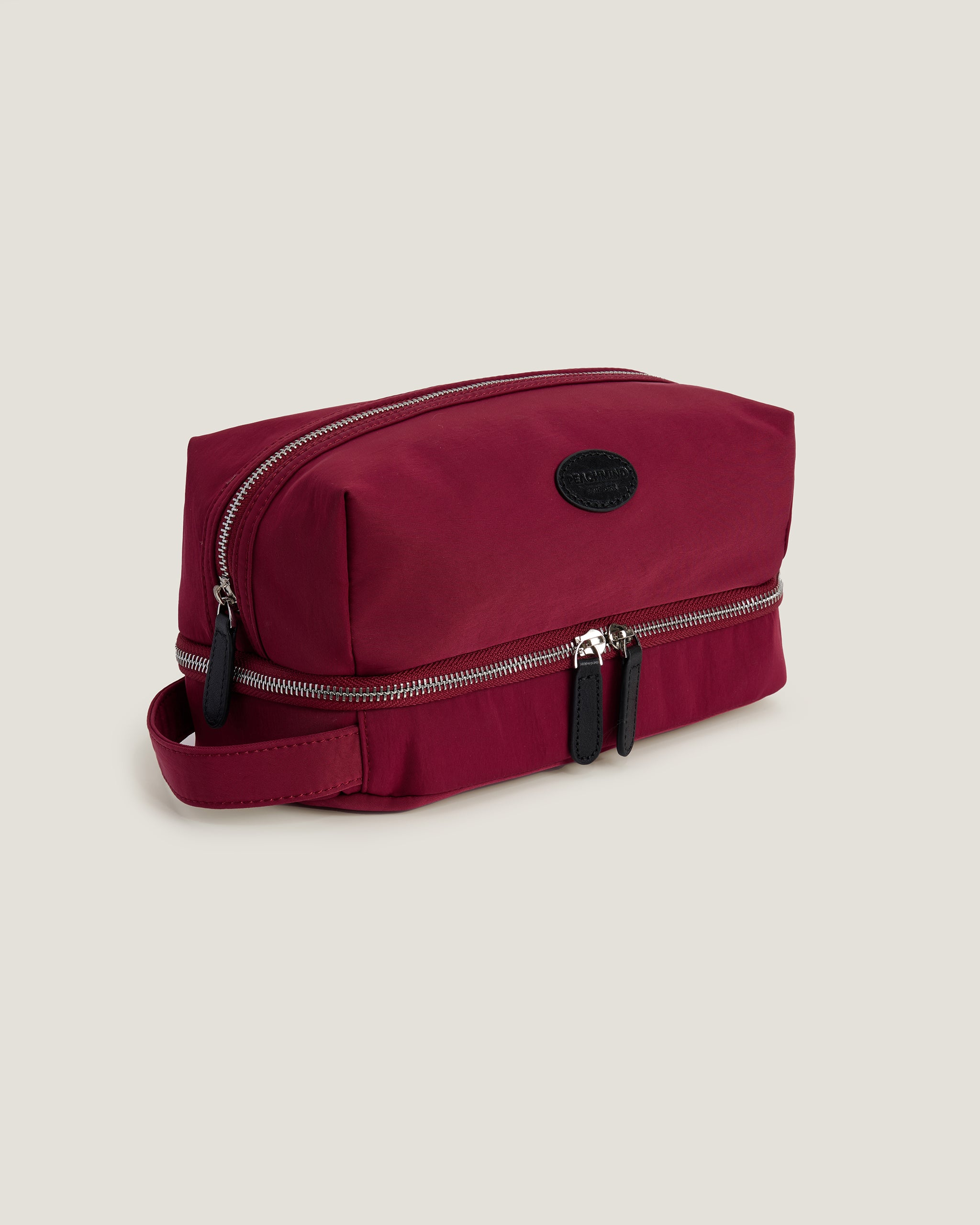 Red toiletry bag with zippers on a beige background