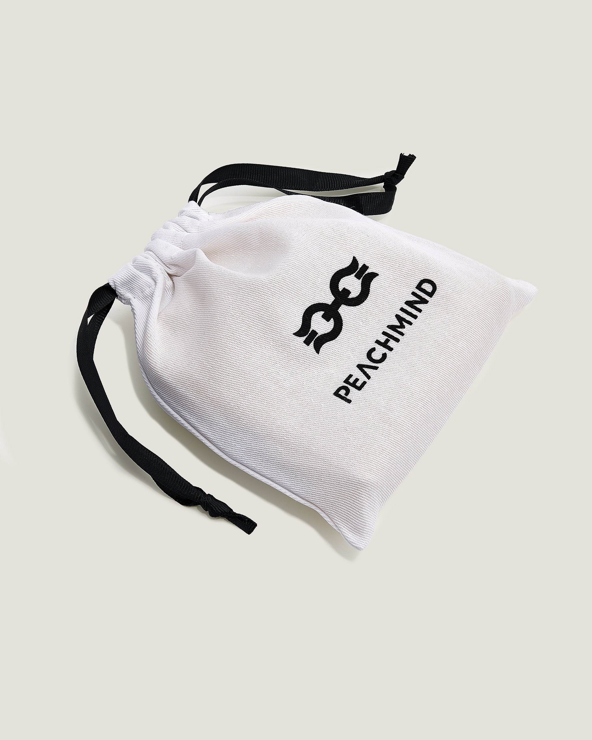 White drawstring pouch with black Peachmind logo on a light beige background