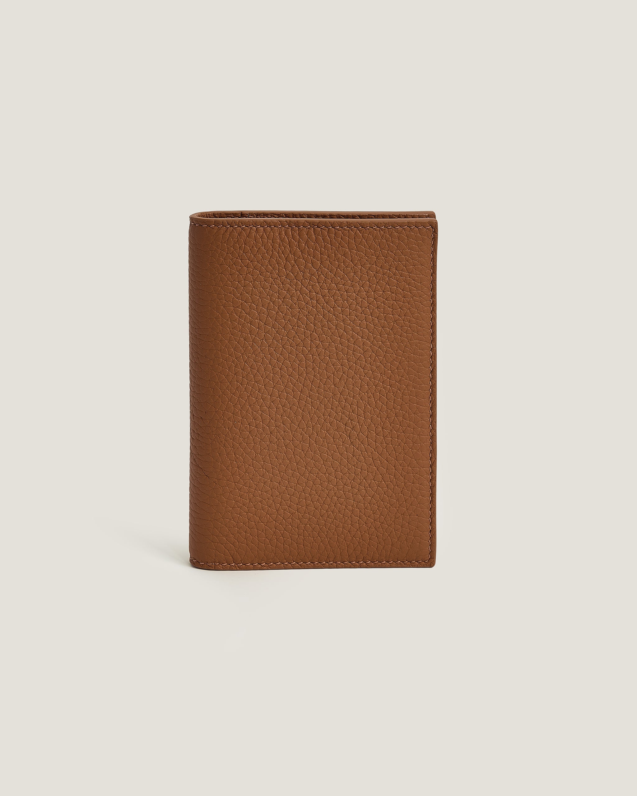 Brown leather passport wallet on a light beige background